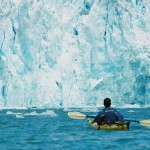 A student paddles by a glacier in the Alaskan rain forest.
