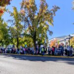 Man holds Liars, Fire Them All sign while other protestors line the streets in Ashland, Oregon's town center
