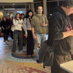 A line of students waits to check-in at Hannon Library's main entrance