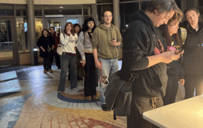 A line of students waits to check-in at Hannon Library's main entrance