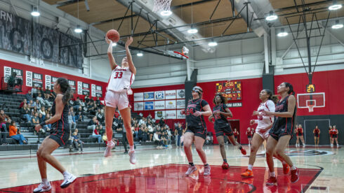 Surrounded by opposing players, SOU freshman guard Millie Day shoots from the key in a game with Simpson University