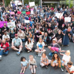 Approximately 100-200 people gather with protest signs in front of Southern Oregon University's Hannon Library